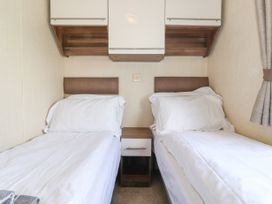 A bedroom with two single beds separated by a small nightstand at 31 Forest Views in Moota near Aspatria