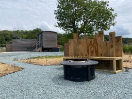 An outdoor area with a fire pit and wooden bench at Hawkstone in Kenstone near Hodnet