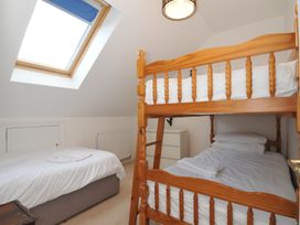 A bedroom with a bunk bed and a double bed at 2 Glyddins 1910, Rock