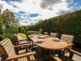An outdoor dining setup with wooden table and chairs at 2 Glyddins 1910, Rock