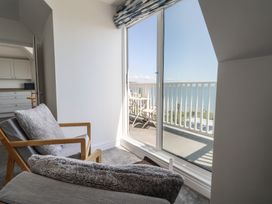 A living room with a chair and sliding door leading to a balcony at 3 Harbour Heights in Lyme Regis