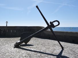 An anchor on cobblestone near the sea with boats at 3 Harbour Heights Lyme Regis