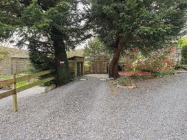 A gravel driveway with a wooden gate and trees at Haystacks in Troutbeck