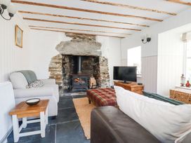 A living room with a wood burning stove in a stone fireplace two sofas a wooden side table and a television on a wooden cabinet at Hilldene in Treknow