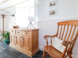 A wooden chair with a cushion next to a wooden cabinet with a lamp and a woven basket on top in a room at Hilldene in Treknow