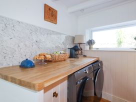 A laundry room with a wooden countertop washing machine dryer basket with scones and a coffee machine at Hilldene in Treknow