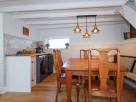 A dining area with wooden table and chairs next to a countertop with washing machine and dryer under a window at Hilldene Treknow