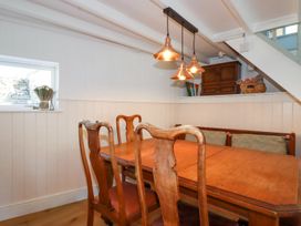 A dining area with wooden table and chairs under pendant lights at Hilldene in Treknow