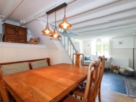 A dining area with wooden table and chairs next to a living area with armchairs under a window at Hilldene in Treknow