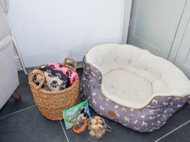 A pet bed with dog treat jar and basket of blankets on the floor in a corner at Hilldene in Treknow