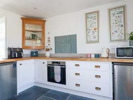 A kitchen with white cabinets wooden countertop oven microwave kettle and two framed pictures on the wall at Hilldene in Treknow