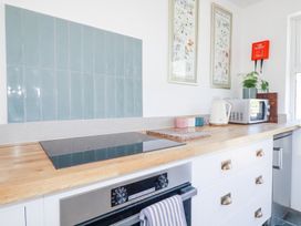 A kitchen countertop with a stove, oven, kettle, microwave, plant, and wall decorations at Hilldene in Treknow