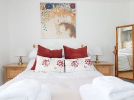 A bedroom with a bed with pillows and lamps on wooden bedside tables and a mirror reflecting a dresser at Hilldene in Treknow