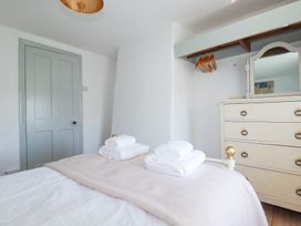 A bedroom with a bed with folded towels a chest of drawers with a mirror and a hanging rail with wooden hangers at Hilldene in Treknow