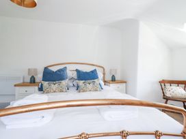 A bedroom with a metal framed bed white bedding blue and patterned pillows two bedside tables with lamps and a wooden chair with a pillow at Hilldene in Treknow