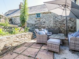 An outdoor patio area with wicker furniture including chairs and a table under a large umbrella at Hilldene in Treknow