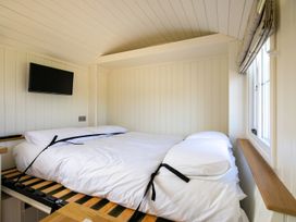 A bedroom with a white bed and pillows a wall-mounted TV and a window with a roller blind at Strathmore in Burnside near Forfar