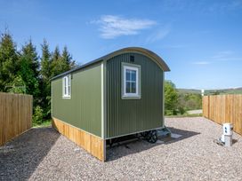 A green mobile cabin with white windows on a gravel area surrounded by wooden fences at Strathmore Burnside near Forfar