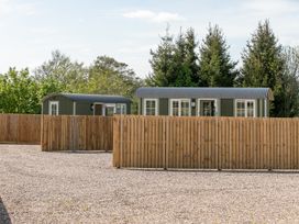 Two green shepherd huts with corrugated roofs behind a wooden fence on gravel at Strathmore Burnside near Forfar