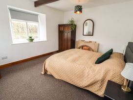 A bedroom with a bed and wardrobe at Honeysuckle Cottage, Crookham near Cornhill-On-Tweed