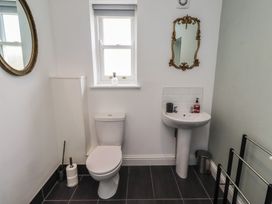 A bathroom with a toilet, sink, and mirror at Honeysuckle Cottage, Crookham near Cornhill-On-Tweed