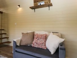 A grey sofa with three cushions under a wall shelf with a projector at Longlands Lodge Longlands near Caldbeck