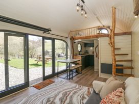 A small living space with sofa table and benches loft bed and wooden spiral staircase at Longlands Lodge in Longlands near Caldbeck