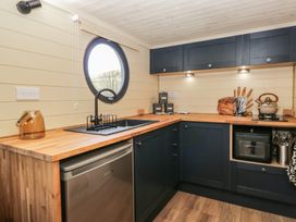 A kitchen with wooden countertops a round window a black sink dark cabinets and various kitchen utensils at Longlands Lodge Longlands near Caldbeck