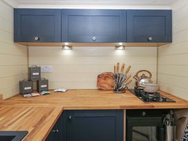 A kitchen countertop with a kettle, cooking pot, knife set, cutting board, and storage tins at Longlands Lodge in Longlands near Caldbeck