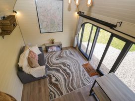 A small living area with a sofa, rug, table, wall map and large arched windows at Longlands Lodge in Longlands near Caldbeck