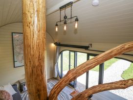 An interior view showing wooden beams with a light fixture above and glass doors leading outside at Longlands Lodge in Longlands near Caldbeck