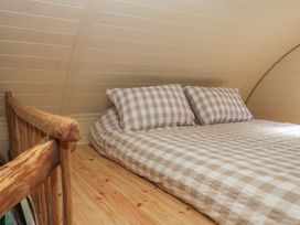 A bedroom with a bed and checkered bedding inside a wooden cabin at Longlands Lodge in Longlands near Caldbeck