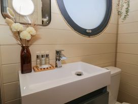 A bathroom sink with a faucet flowers and toiletries near a round window at Longlands Lodge in Longlands near Caldbeck