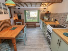 A kitchen with a dining table and various appliances at 2 Strand Cottages in Carmarthen
