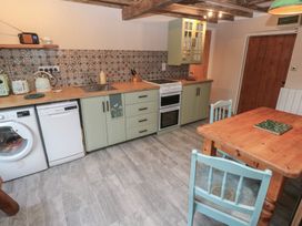 A kitchen with appliances and a dining table at 2 Strand Cottages in Carmarthen