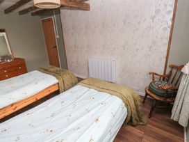 A bedroom with two beds and a wooden dresser at 2 Strand Cottages in Carmarthen