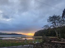A view of a sunset over water with trees at 2 Strand Cottages in Laugharne