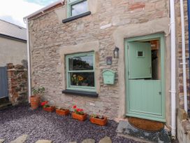 An entrance with a green door and flower pots at 2 Strand Cottages in Laugharne