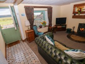 A living room with a sofa and television at 2 Strand Cottages in Laugharne