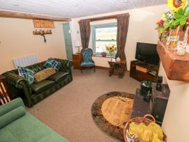 A living room with a sofa, chair, and television at 2 Strand Cottages, Laugharne