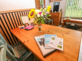 A dining room with a wooden table and flowers at 2 Strand Cottages in Laugharne