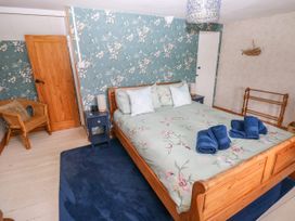 A bedroom with a bed and chair at 2 Strand Cottages in Laugharne