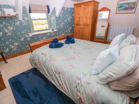 A bedroom with a bed and wardrobe at 2 Strand Cottages Laugharne