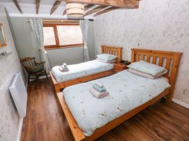 A bedroom with two single beds and a chair at 2 Strand Cottages in Laugharne