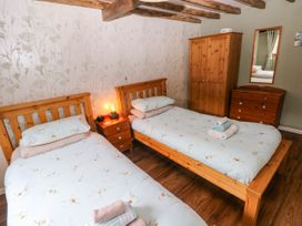 A bedroom with two single beds and a wardrobe at 2 Strand Cottages in Laugharne