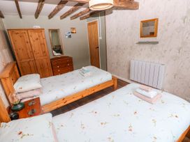 A bedroom with two beds and wooden furniture at 2 Strand Cottages Laugharne