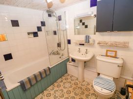 A bathroom with a bathtub, shower, sink, and toilet at 2 Strand Cottages in Laugharne