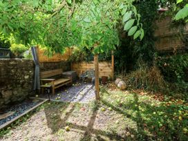 A garden with a bench and table surrounded by apples at 2 Strand Cottages Laugharne