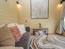 A room with a sofa with cushions a patterned rug a small table with flowers and a blanket under it a large map on the wall at Binsey Lodge in Longlands near Caldbeck