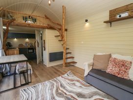 A living area with a sofa cushions rug staircase and kitchen at Binsey Lodge in Longlands near Caldbeck